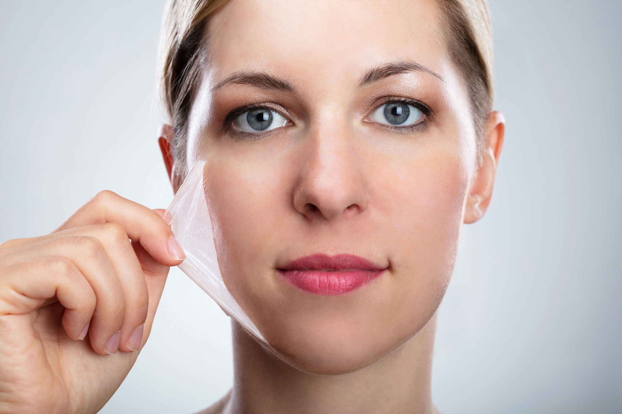 Portrait Of A Beautiful Young Woman Removing Peeling Mask